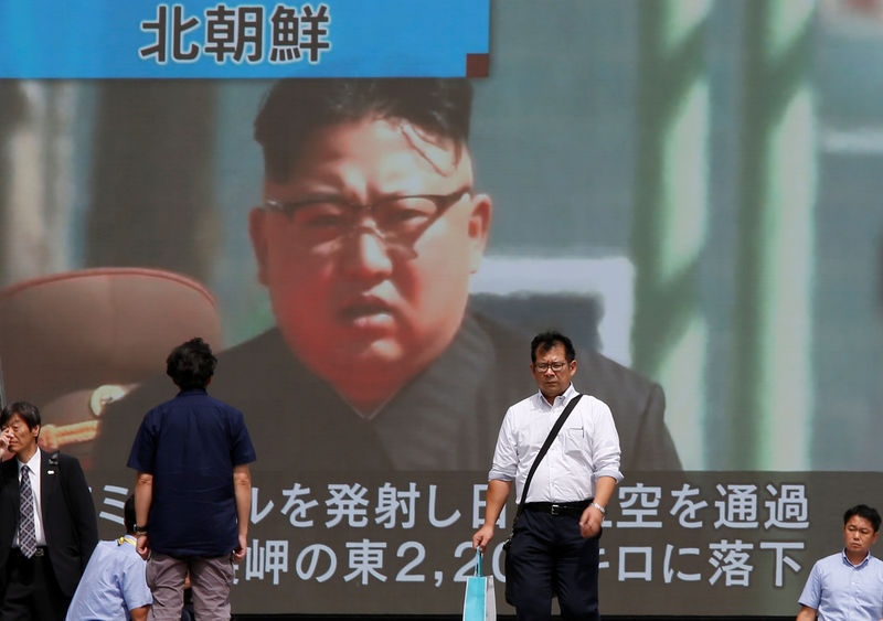 © Reuters. Passersby walk past a TV screen reporting news about North Korea's missile launch in Tokyo