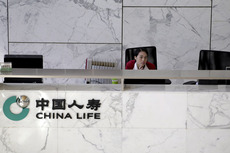 © Reuters. FILE PHOTO: An employee sits at the reception of the headquarters building of China Life insurance in Beijing