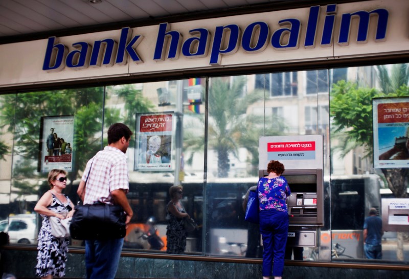 © Reuters. FILE PHOTO: A woman uses an ATM outside a Bank Hapoalim branch in Tel Aviv