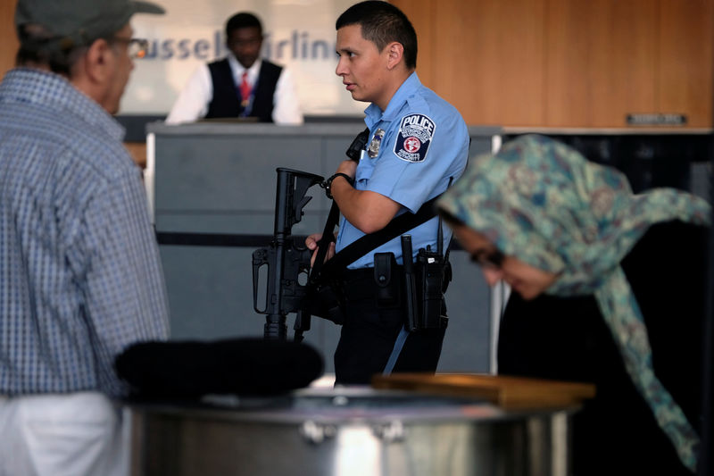 © Reuters. A police officer patrols with a rifle as passengers gather their luggage at Dulles International Airport in Dulles, Virginia, U.S.