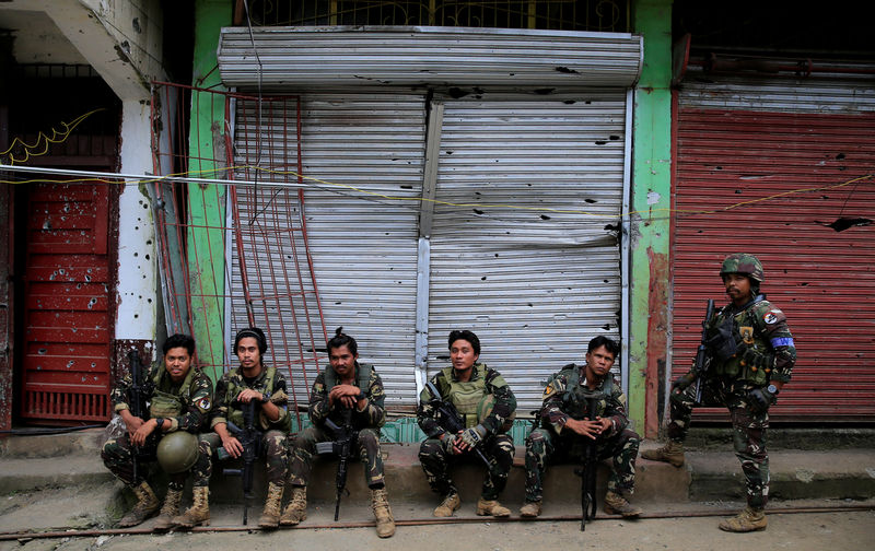 © Reuters. Government soldiers takes a break in front of a damaged building in Sultan Omar Dianalan boulevard at Mapandi district in Marawi city