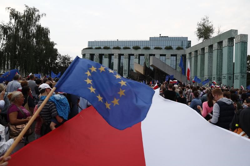 © Reuters. People wave EU and Polish flags during a protest against supreme court legislation in Warsaw