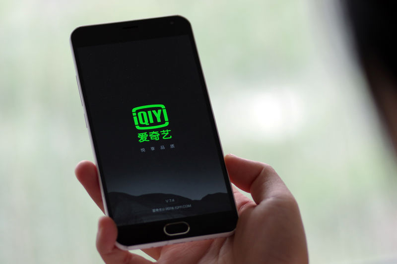 © Reuters. Photo illustration shows a person holding a phone with Baidu Inc's video streaming service iQiyi in Jinan