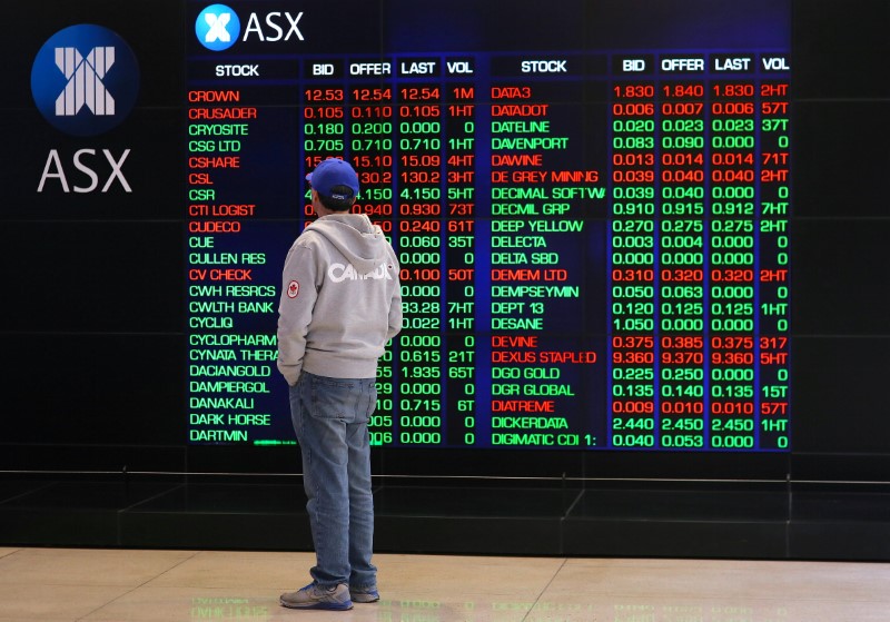 © Reuters. Sydney, un inve4stitore davanti al tabellone dell'Australian Securities Exchange (ASX)