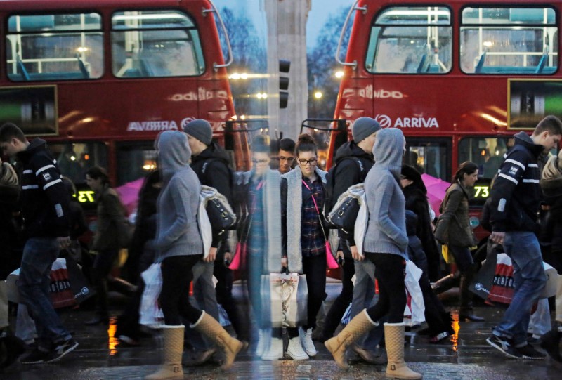 © Reuters. FILE PHOTO:  Shoppers are reflected in a shop window as they walk along Oxford Street in London