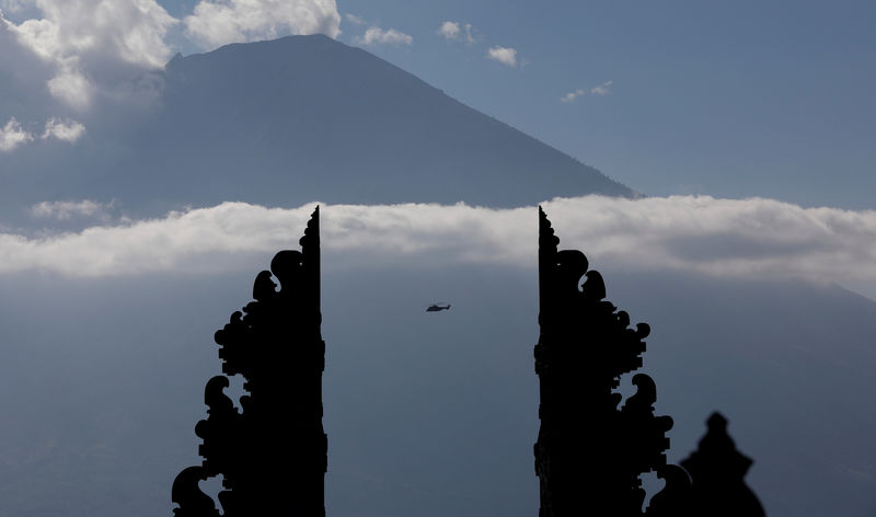 © Reuters. A helicopter, one of three carrying officials including President Joko Widodo, is seen flying near Mount Agung, a volcano on the highest alert level, from Penataran Agung Lempuyang temple in Karangasem Regency on the resort island of Bali