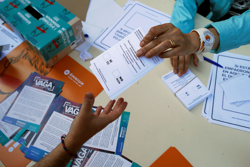 © Reuters. A volunteer gives ballots to a man ahead of the banned October 1 independence referendum in Barcelona