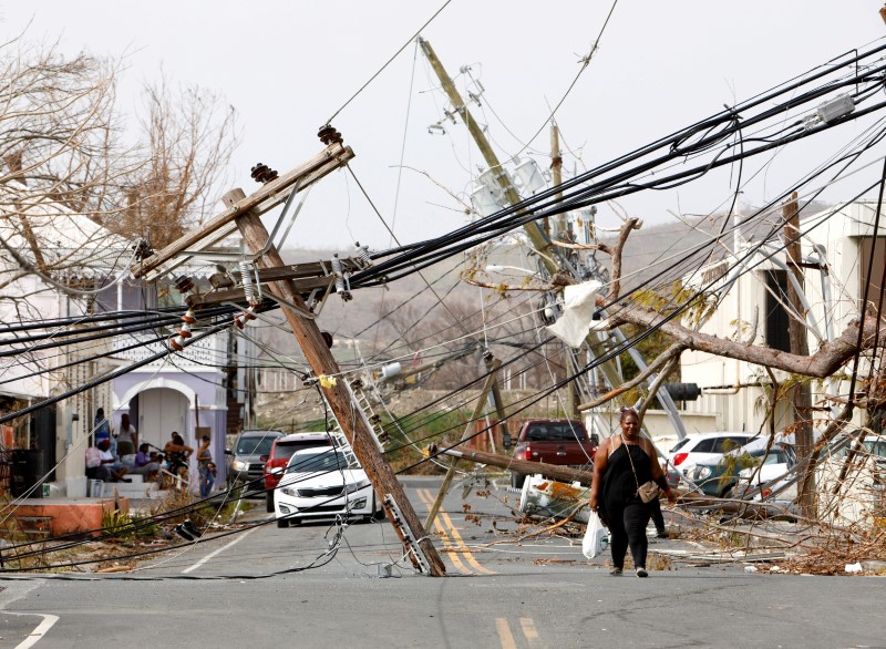 © Reuters. FILE PHOTO: Residents and cars make their way around and under obstacles blocking a main road nearly a week after Hurricane Maria raked the island, in Frederiksted, St. Croix