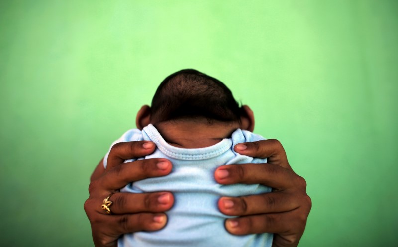© Reuters. A 4-month-old baby born with microcephaly is held by his mother in front of their house in Olinda
