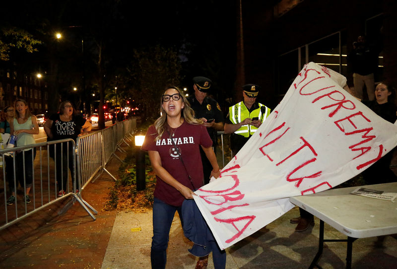 © Reuters. Protesters leave a forum with their banners after protesting inside against U.S. Education Secretary Betsy DeVos at Harvard University's Kennedy School of Government