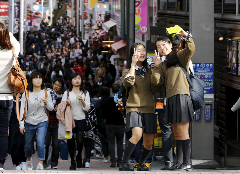 © Reuters. FILE PHOTO: School girls pose for a selfie in the trendy Harajuku district in Tokyo