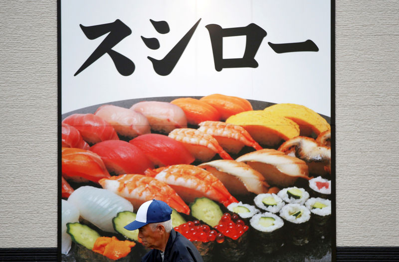 © Reuters. FILE PHOTO: A man walks in front of an advertisement board of sushi restaurant chain Sushiro in Kawaguchi
