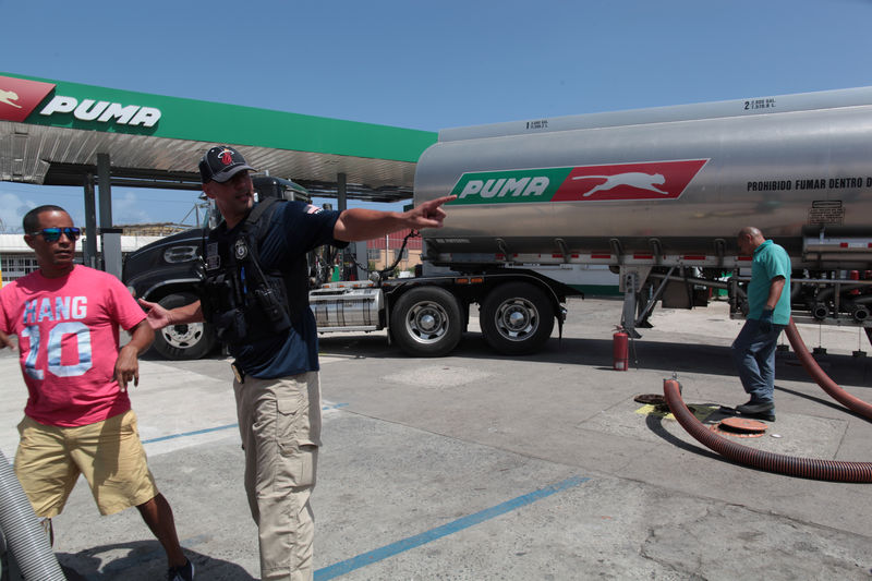 © Reuters. A man is removed by a federal agent from the facilities of a gas station while a truck discharges gas, after the island was hit by Hurricane Maria, in San Juan