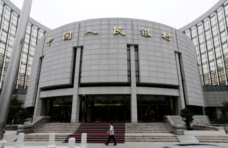 © Reuters. En la imagen de archivo, un miembro del personal camina enfrente a la sede del Banco Popular de China, en Pekín