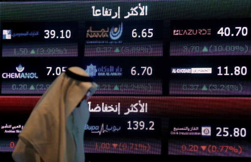 © Reuters. FILE PHOTO: An investor walks past a screen displaying stock information at the Saudi Stock Exchange (Tadawul) in Riyadh