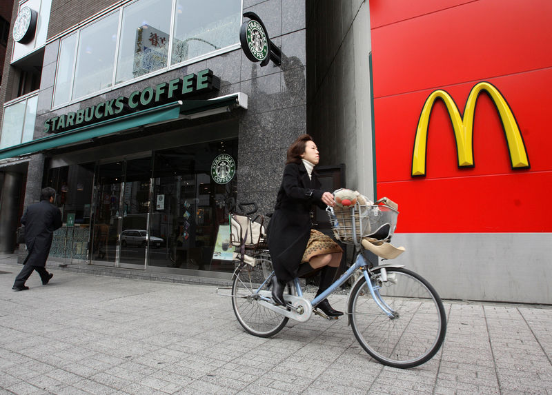 © Reuters. FILE PHOTO: A cyclist rides past branches Starbucks and McDonalds in the Jimbocho district of Tokyo