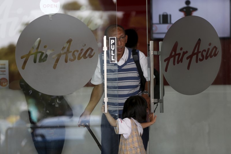 © Reuters. FILE PHOTO - Passengers open a door of AirAsia ticketing office at  Soekarno-Hatta Airport in Jakarta
