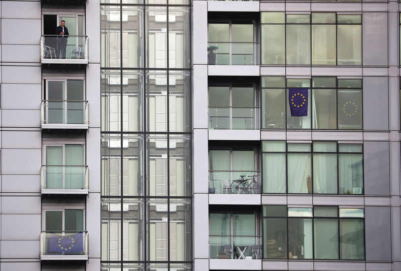 © Reuters. A man stands on a balcony of a building decorated with EU flags overlooking the venue of the Conservative Party's conference in Manchester