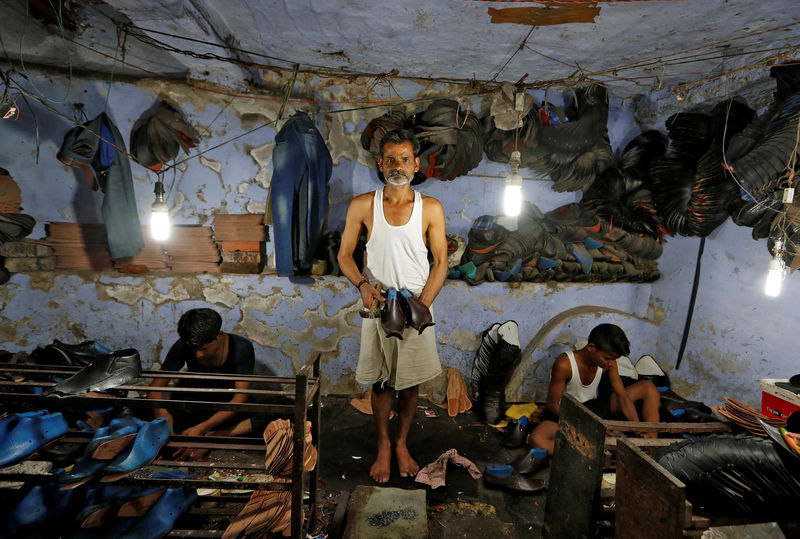 © Reuters. FILE PHOTO: A shoemaker poses for a picture in an underground workshop in Agra