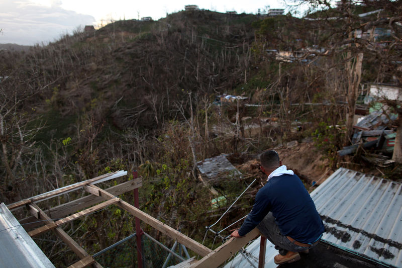 © Reuters. A local resident sits on the roof of his home that was damaged by Hurricane Maria in Guaynabo