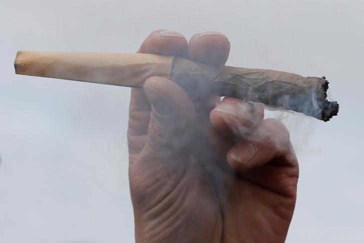 © Reuters. FILE PHOTO - A man holds a marijuana joint during the annual 4/20 marijuana rally on Parliament Hill in Ottawa