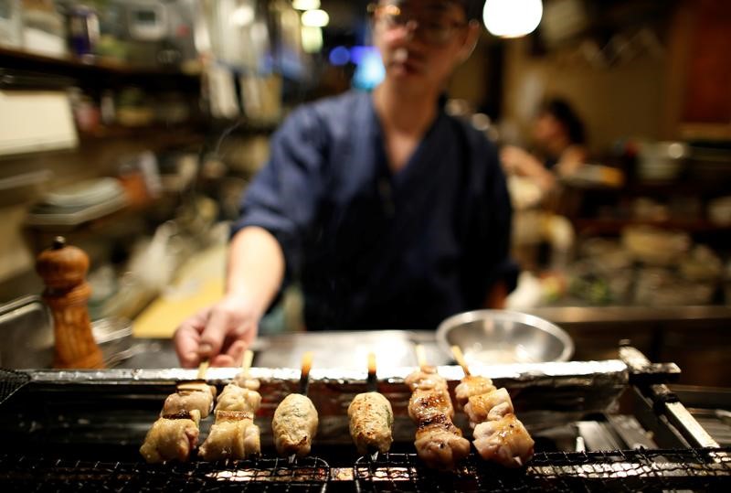 © Reuters. A man cooks a skewered chicken meal, know as Yakitori in Japan, at a Japanese casual style bar and restaurant called Izakaya in Tokyo