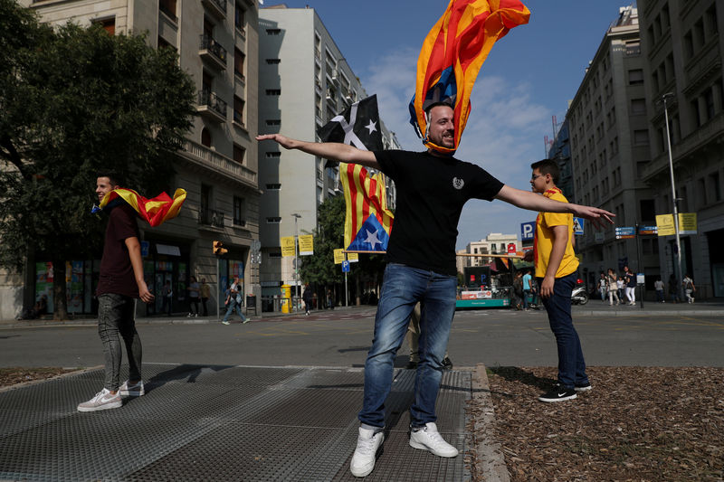© Reuters. People hold on to Catalan separatist flags on top of an air vent two days after the banned independence referendum in Barcelona