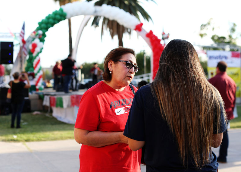 © Reuters. University of Arizona Center for Rural Health Navigator Maria Losoya provides an uninsured woman information about how to get affordable health insurance at the Celebracion de la Independencia de Mexico in Tucson