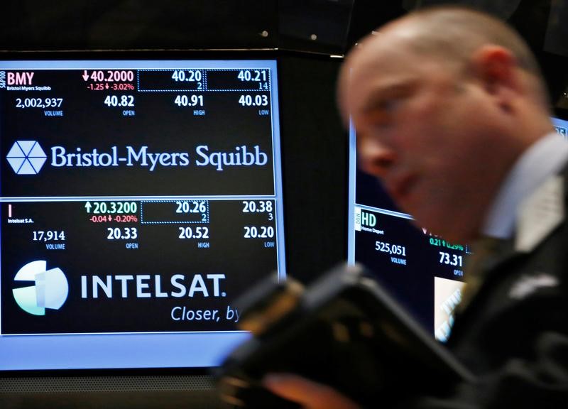 © Reuters. A trader passes by a screen displaying the tickers symbols for Bristol-Myers Squibb and Intelsat, Ltd. on the floor at the New York Stock Exchange