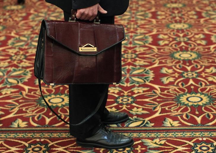 © Reuters. A man holds his briefcase while waiting in line during a job fair in Melville, New York