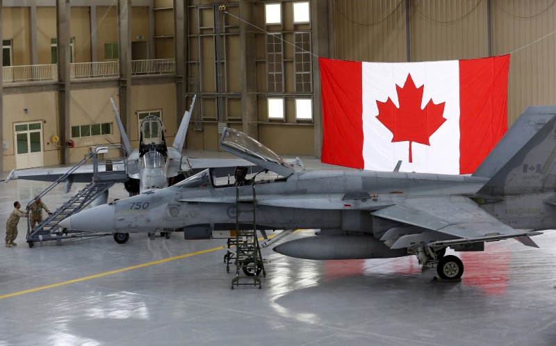 © Reuters. FILE PHOTO: Members of the Canadian Forces push a ladder up to a Canadian F-18 Hornet fighter at a military base in Kuwait