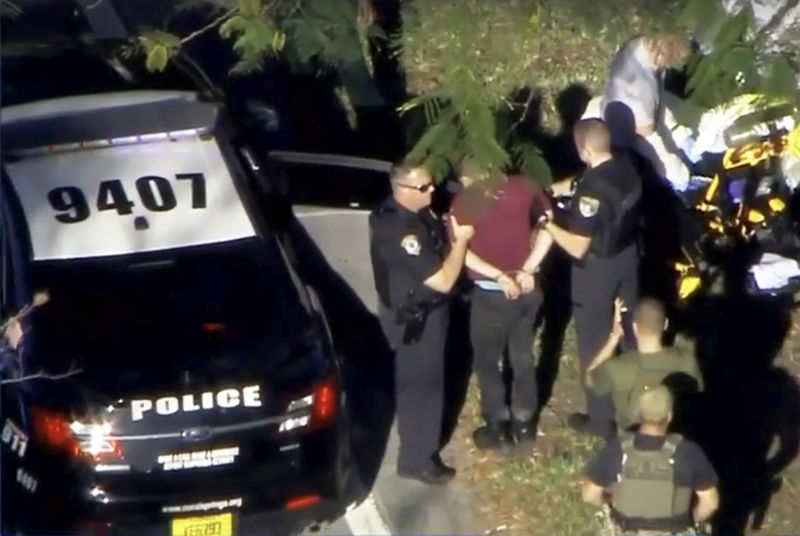 © Reuters. Un hombre esposado es conducido por la policía cerca de la escuela secundaria Marjory Stoneman Douglas luego de un tiroteo en Parkland, Florida