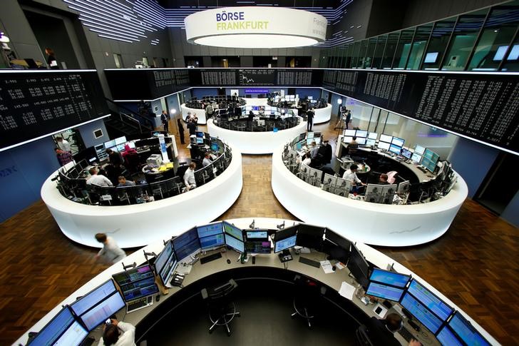 © Reuters. FILE PHOTO: Traders work at their desks in front of the German share price index, DAX board, at the stock exchange in Frankfurt