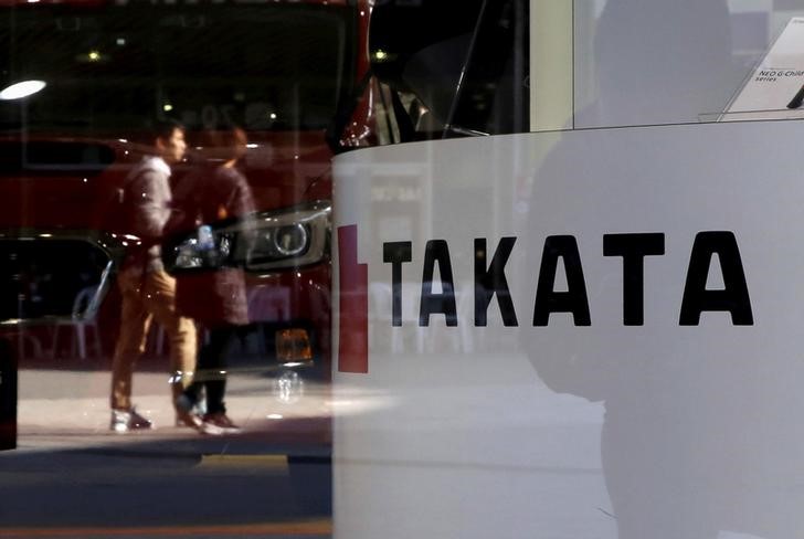 © Reuters. FILE PHOTO -  A logo of Takata Corp is seen with its display as people are reflected in a window at a showroom for vehicles in Tokyo