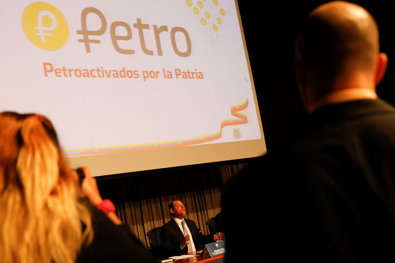© Reuters. The new Venezuelan cryptocurrency the Petro logo is seen as Minister for University Education, Science and Technology Hugbel Roa talks to the media during a news conference in Caracas