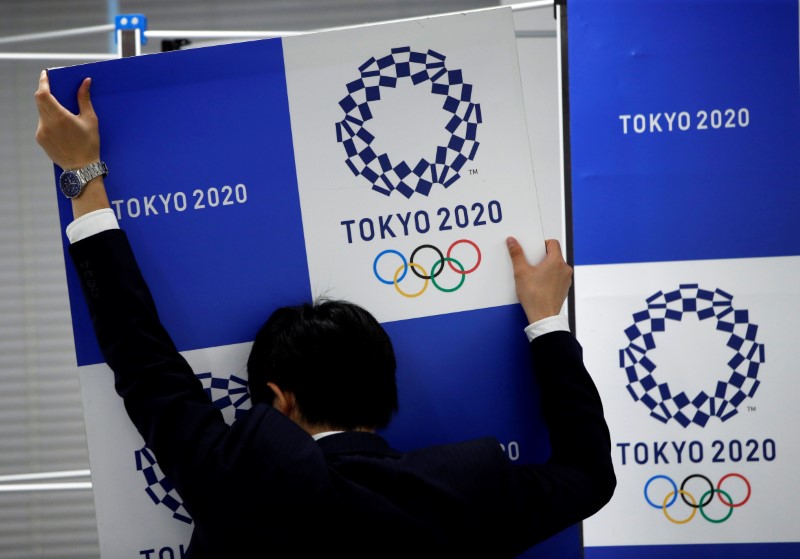 © Reuters. A staff takes out a banner featuring Tokyo 2020 Olympics emblem from the wall after a news conference hosted by IOC Vice President John Coates and President of Tokyo 2020 Olympic and Paralympic organising committee Yoshiro