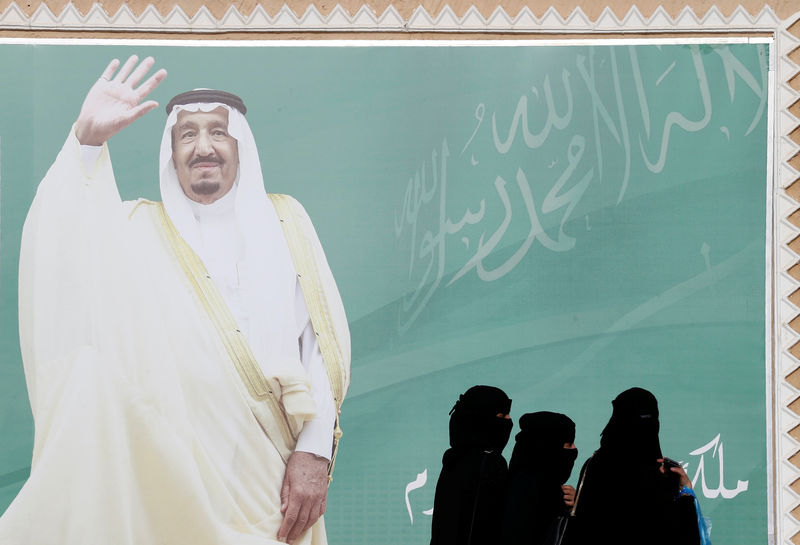 © Reuters. Mulheres passam em frente a poster com o rei da Arábia Saudita Salman bin Abdulaziz Al Saud. 12/02/2018. REUTERS/Faisal Al Nasser