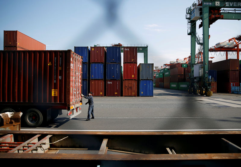 © Reuters. FILE PHOTO: A man works between shipping containers at a port in Tokyo, Japan