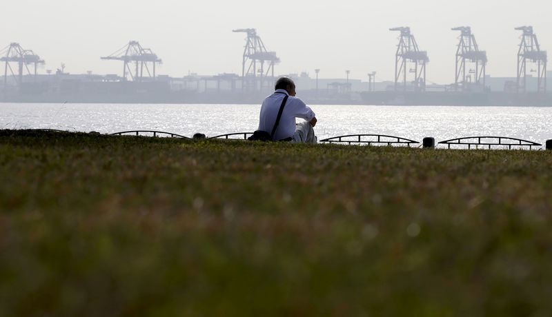 © Reuters. FILE PHOTO: A man sits near a cargo area at a port in Tokyo