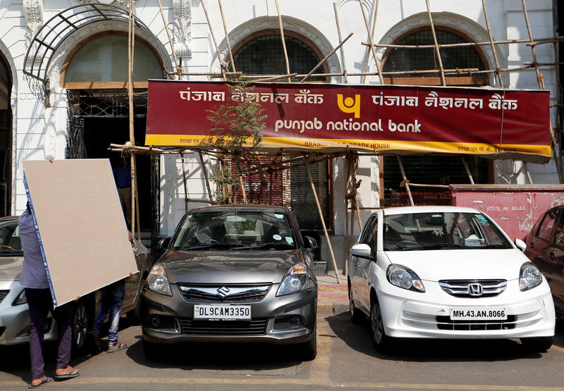 © Reuters. People carry plywood sheets outside a Punjab National Bank branch after it was sealed by India's federal police in Mumbai