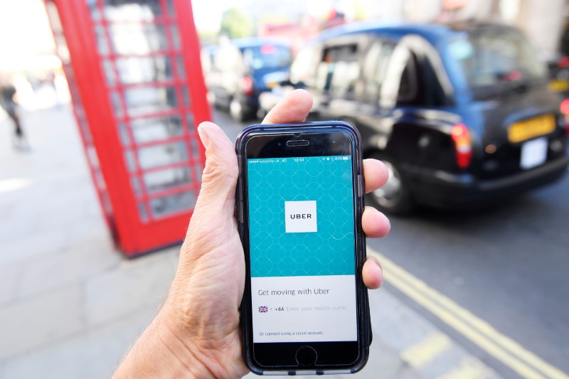 © Reuters. A photo illustration shows a London taxi passing as the Uber app logo is displayed on a mobile telephone, as it is held up for a posed photograph in central London