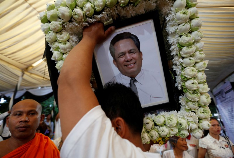 © Reuters. FILE PHOTO: A man holds portrait of Kem Ley, an anti-government figure and the head of a grassroots advocacy group, "Khmer for Khmer", shot dead on July 10, as they attend a funeral procession to carry his body to his hometown in Phnom Penh
