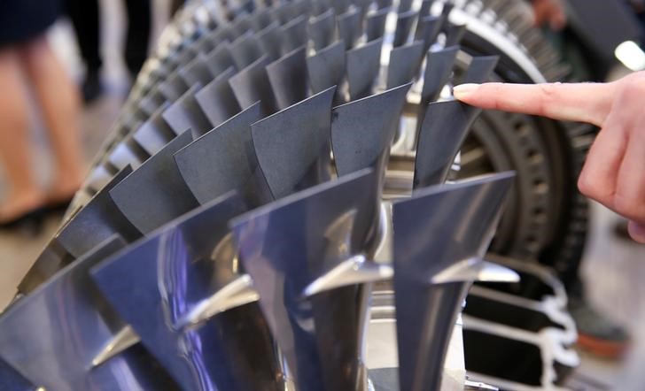 © Reuters. A staff poses with blades of a MTU Aero Engines V 2500 HPC aircraft engine are pictured at the ILA Berlin Air Show in Schoenefeld