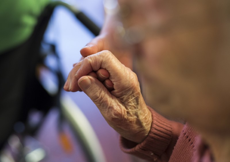 © Reuters. FILE PHOTO: Resident holds hand of nurse at SenVital elderly home in Kleinmachnow outside Berlin