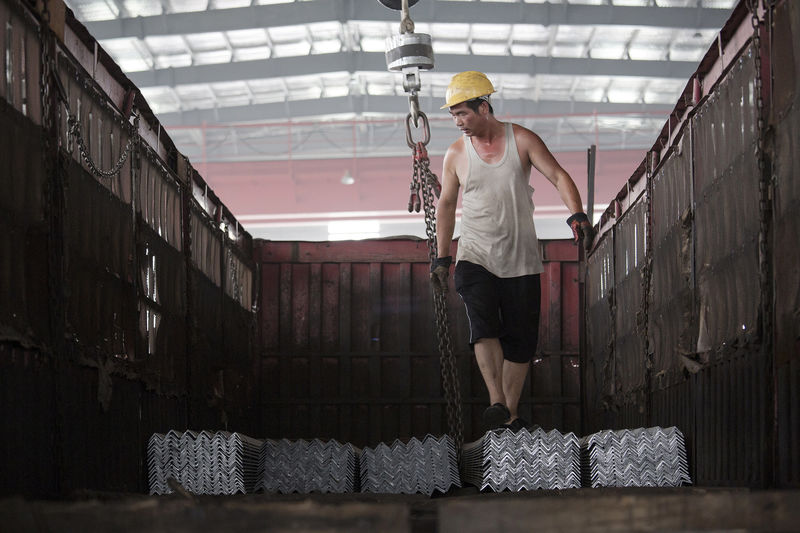 © Reuters. FILE PHOTO: A worker helps load steel bars onto a truck at warehouse in Tangshan in China's Hebei Province