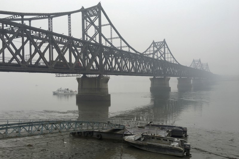 © Reuters. FILE PHOTO: Trucks move across the bridge linking North Korea with the Chinese border city of Dandong