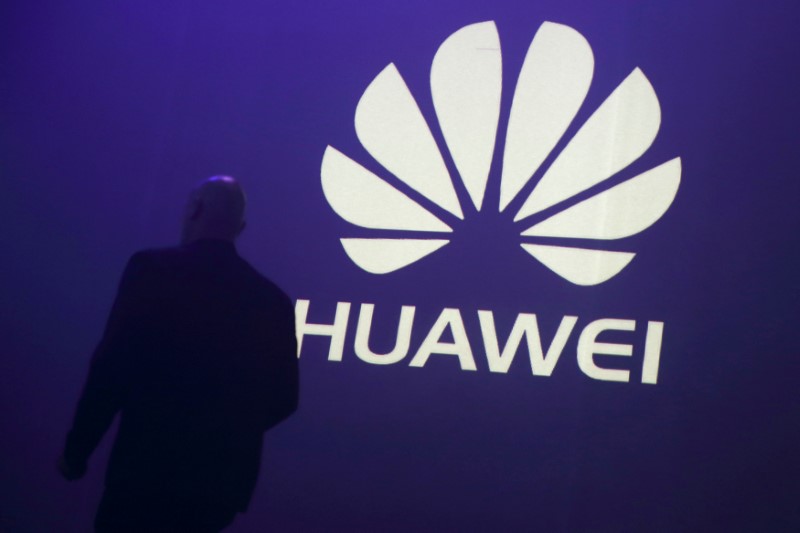 © Reuters. FILE PHOTO - A man walks past a logo during the presentation the Huawei's new smartphone, the Ascend P7, launched by China's Huawei Technologies in Paris