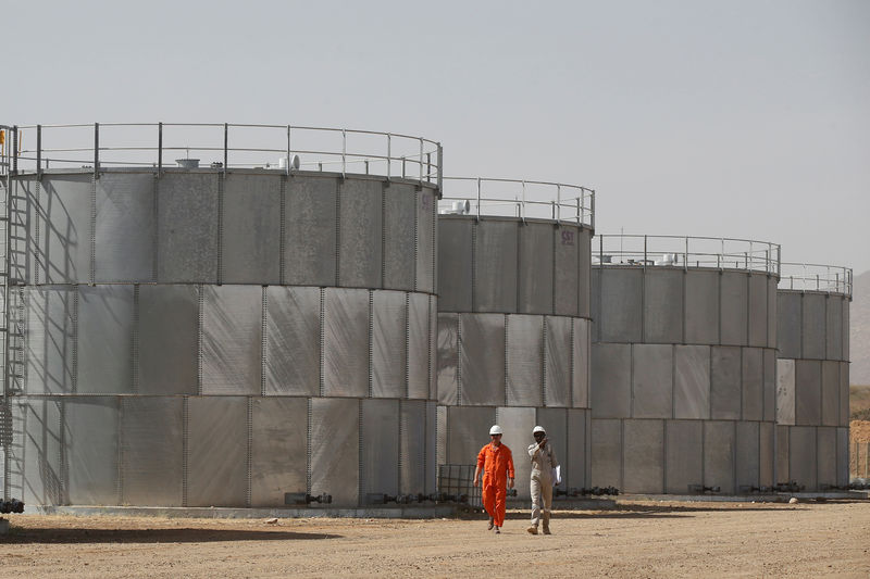 © Reuters. Workers walk past storage tanks at Tullow Oil's Ngamia 8 drilling site in Lokichar