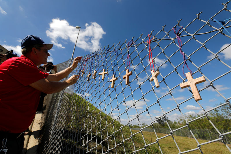 © Reuters. Chaplain places crosses for the victims of the Marjory Stoneman Douglas High School shooting in Parkland