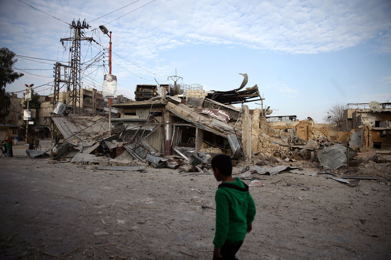 © Reuters. En la imagen de archivo, un niño mira escombros de un edificio en Duma, Guta Oriental, Siria